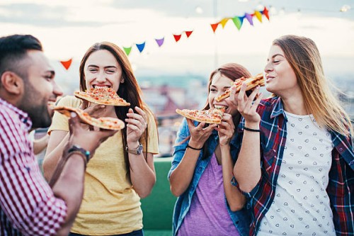 young people eating pizza on a rooftop party - junk food stockfoto's en -beelden