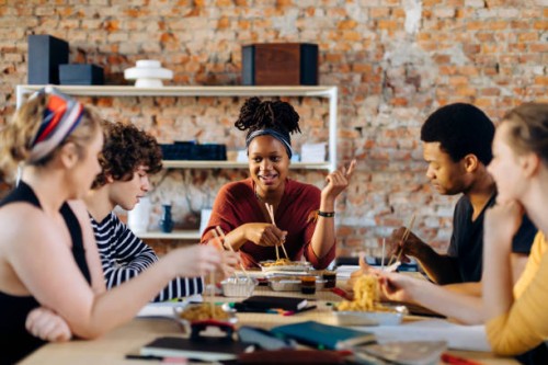 young people sitting together at table having lunch break - junk food stock pictures, royalty-free photos & images