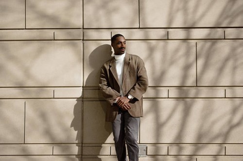 young professional standing confidently against a sunlit wall outdoors - fashion stock pictures, royalty-free photos & images