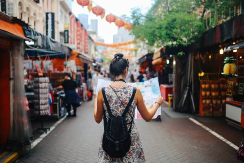 young solo traveler woman in singapore street market checking the map - travel stock pictures, royalty-free photos & images