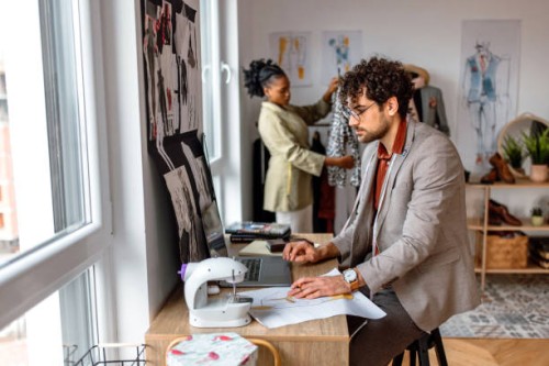 young tailor using laptop for work in his workshop. - fashion stock pictures, royalty-free photos & images