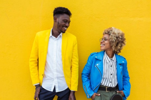 young trendy black multiracial friends looking each other over yellow background. african man and latin american woman standing together outdoors. - fashion fotografías e imágenes de stock