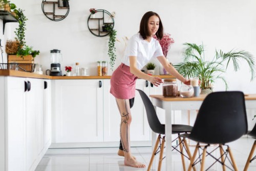 young woman amputee with prosthesis arranging food and kitchen utensils at home - home decoration stock pictures, royalty-free photos & images