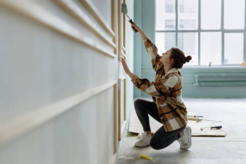 young woman applying paint on wall in apartment - home decoration stock pictures, royalty-free photos & images