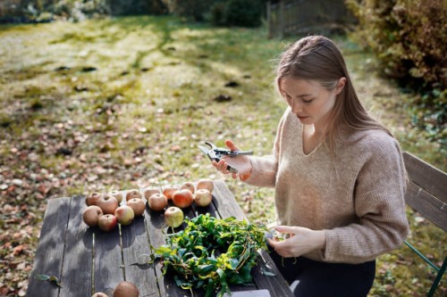 young woman arranging wreath in garden - garden decoration stock-fotos und bilder