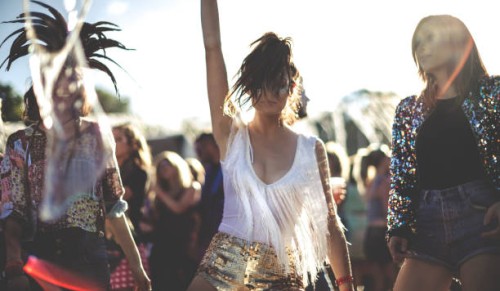 young woman at a summer music festival wearing golden sequinned hot pants, dancing among the crowd. - fashion stock pictures, royalty-free photos & images