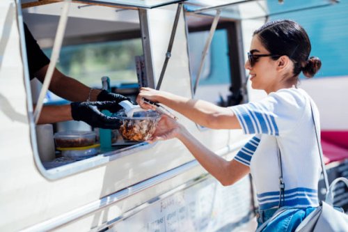 young woman buying take away food from a street food stand - junk food stock pictures, royalty-free photos & images
