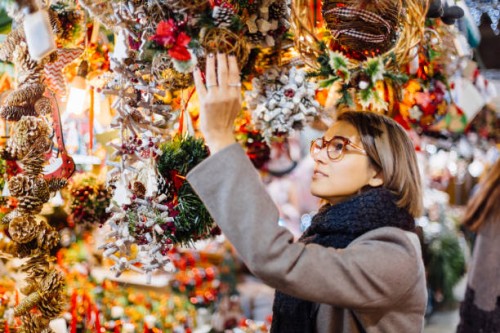 young woman choosing christmas decoration on a christmas market in barcelona, spain - home decoration stock pictures, royalty-free photos & images