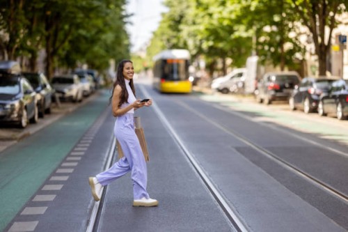 young woman crossing the street with mobile phone. - fashion photos et images de collection