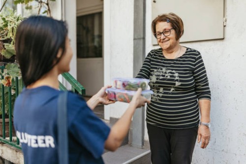 young woman delivering food to senior citizen - food stock pictures, royalty-free photos & images