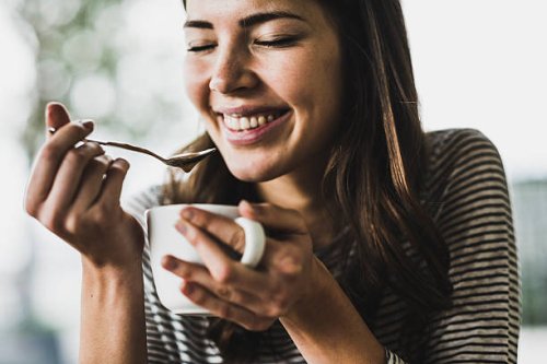 young woman drinking cappuccino, spooning milk froth - coffee stockfoto's en -beelden