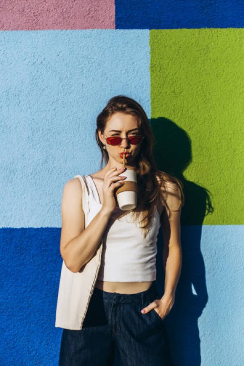 young woman drinking coffee against squared color wall. - fashion stock pictures, royalty-free photos & images