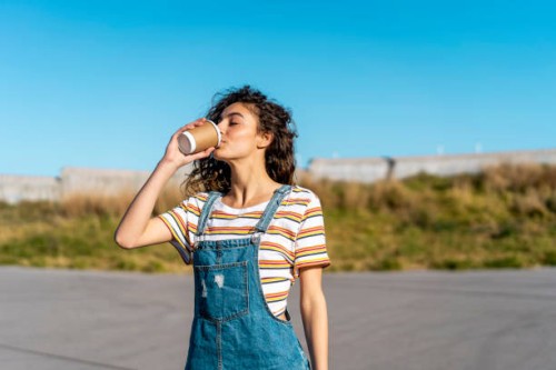 young woman drinking coffee from a disposable cup - junk food stock pictures, royalty-free photos & images