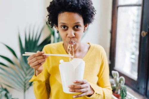 young woman eating asian noodles for lunch with chopsticks - junk food stock pictures, royalty-free photos & images
