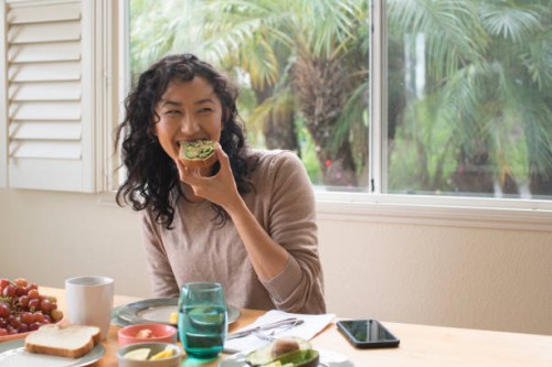 young woman eating avocado toast at home - food stock pictures, royalty-free photos & images