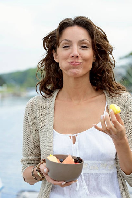 young woman eating fruit on dock, smiling, portrait, close-up - food stock pictures, royalty-free photos & images