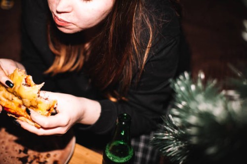 young woman eating homemade pizza with beer sitting by christmas tree - food stock pictures, royalty-free photos & images
