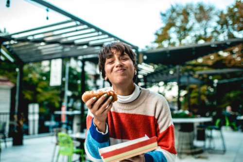 young woman eating hot dog on the street - junk food stock pictures, royalty-free photos & images