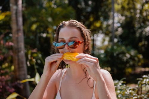 young woman eating mango on vacation - food stock pictures, royalty-free photos & images