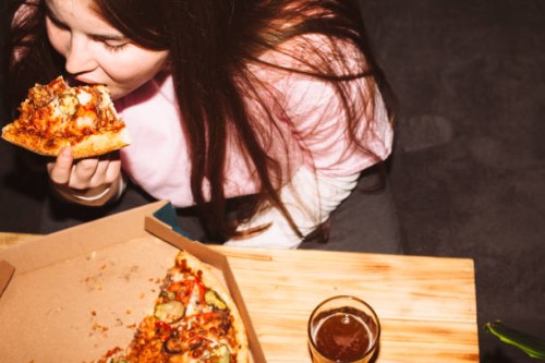 young woman eating pizza and drinking craft beer at house party - junk food stock pictures, royalty-free photos & images