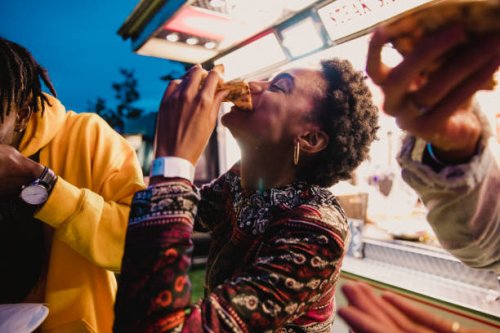 young woman eating pizza at festival - junk food stock pictures, royalty-free photos & images