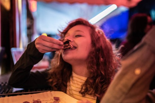 young woman eating pizza outdoors at night - junk food stock pictures, royalty-free photos & images