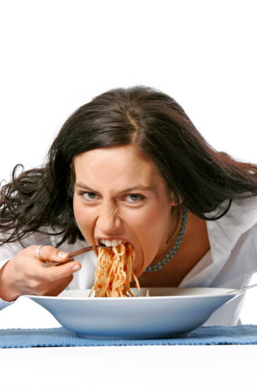 young woman eating spaghetti - junk food stockfoto's en -beelden