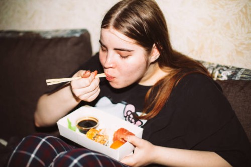 young woman eating sushi at house party - junk food stock pictures, royalty-free photos & images