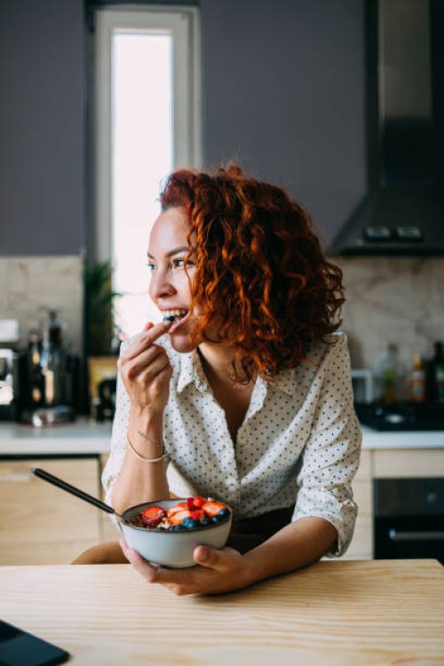 young woman enjoying a healthy breakfast at home - food stockfoto's en -beelden
