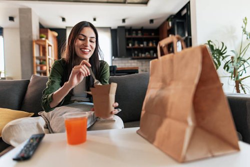 young woman enjoying takeaway food at home - junk food stock pictures, royalty-free photos & images