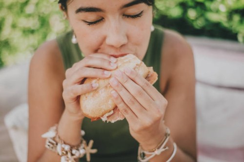 young woman enjoys a serrano ham sandwich outdoors - food stock pictures, royalty-free photos & images