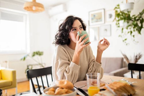young woman having breakfast at home drinking coffee - coffee stockfoto's en -beelden