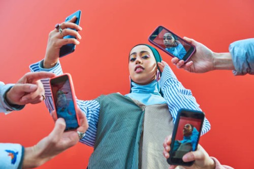 young woman having picture taken by multiple smartphones. - fashion stock pictures, royalty-free photos & images