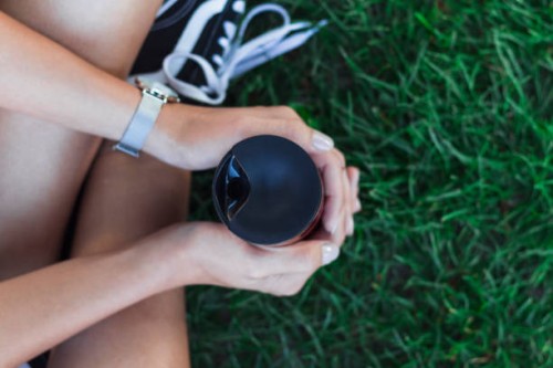 young woman holding reusable coffee cup. - junk food stock pictures, royalty-free photos & images