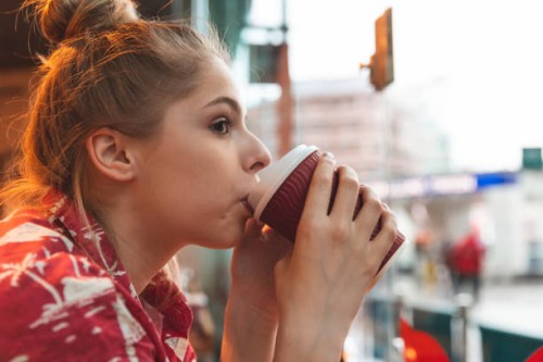 young woman in a cafe drinking a coffee - junk food stock pictures, royalty-free photos & images