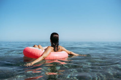 young woman in a sprinkled doughnut float at the beach - fashion stock pictures, royalty-free photos & images