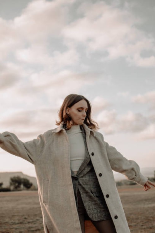 young woman in warm clothing looking away while in the meadow at sunrise standing against sky,france - fashion stock pictures, royalty-free photos & images