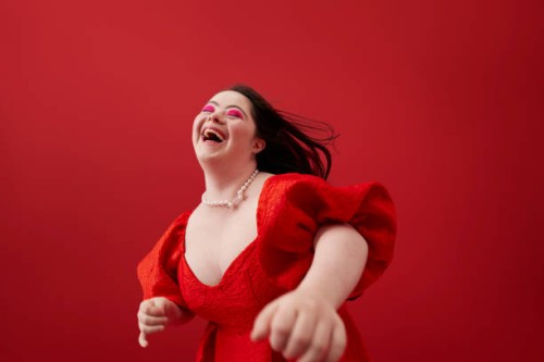 young woman laughing against red background - fashion stock pictures, royalty-free photos & images