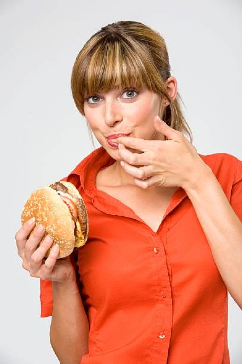 young woman licking finger, holding hamburger, portrait, close-up - junk food stock pictures, royalty-free photos & images