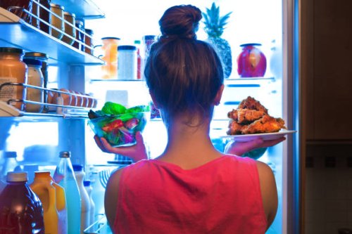 young woman making choices for a healthy salad or junk food fried chicken - junk food stock pictures, royalty-free photos & images