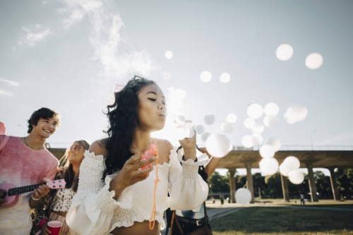 young woman making smoke bubbles while enjoying with friends at music concert - concert stock pictures, royalty-free photos & images
