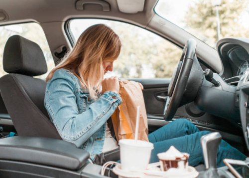 young woman opening take out food bag in a car - junk food stock pictures, royalty-free photos & images