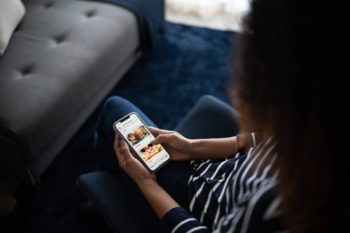 young woman ordering food online with smartphone at home - junk food stock pictures, royalty-free photos & images