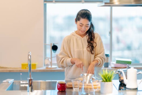 young woman preparing breakfast in kitchen - food stock pictures, royalty-free photos & images