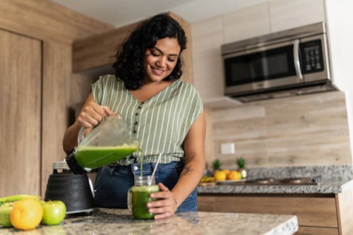 young woman preparing detox juice in kitchen at home - food stock pictures, royalty-free photos & images
