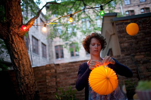 young woman preparing paper lantern in back yard for garden party - garden decoration stock pictures, royalty-free photos & images