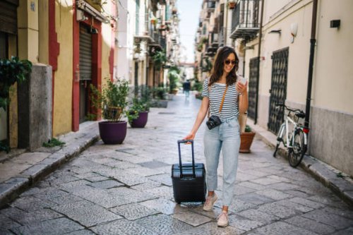 young woman pulls suitcase down cobblestone street - travel stock pictures, royalty-free photos & images