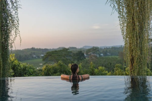 young woman relaxes on edge of swimming pool - travel stock-fotos und bilder