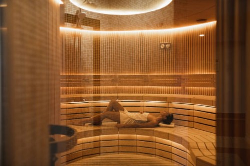 young woman relaxing and sweating in hot sauna wrapped in towel. - fashion stock pictures, royalty-free photos & images