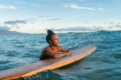 young woman resting on her surfboard waiting for a wave - travel stock pictures, royalty-free photos & images